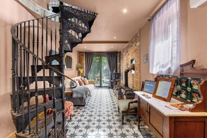 A staircase with ornate metal railings, a sofa, a table with a sign, and a patterned floor. - Keepers Lodge - Sleeps 4 (Nottingham)
