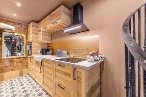A modern kitchen with wooden cabinets, a stainless steel sink, and a black range hood. - Keepers Lodge - Sleeps 4 (Nottingham)