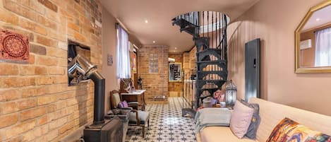 A cozy interior with a brick wall, a spiral staircase, a sofa, and a tiled floor.