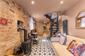 A cozy interior with a brick wall, a spiral staircase, a sofa, and a tiled floor.