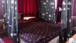 A room with a bed, curtains, a bedside table, and a lamp. - Room-charming Family Room in South Patt (Pattaya)