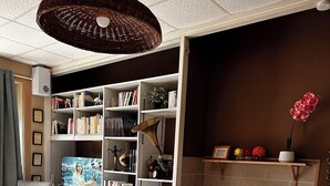 A modern living room with a dining area, bookshelves, a television, and a kitchen counter.