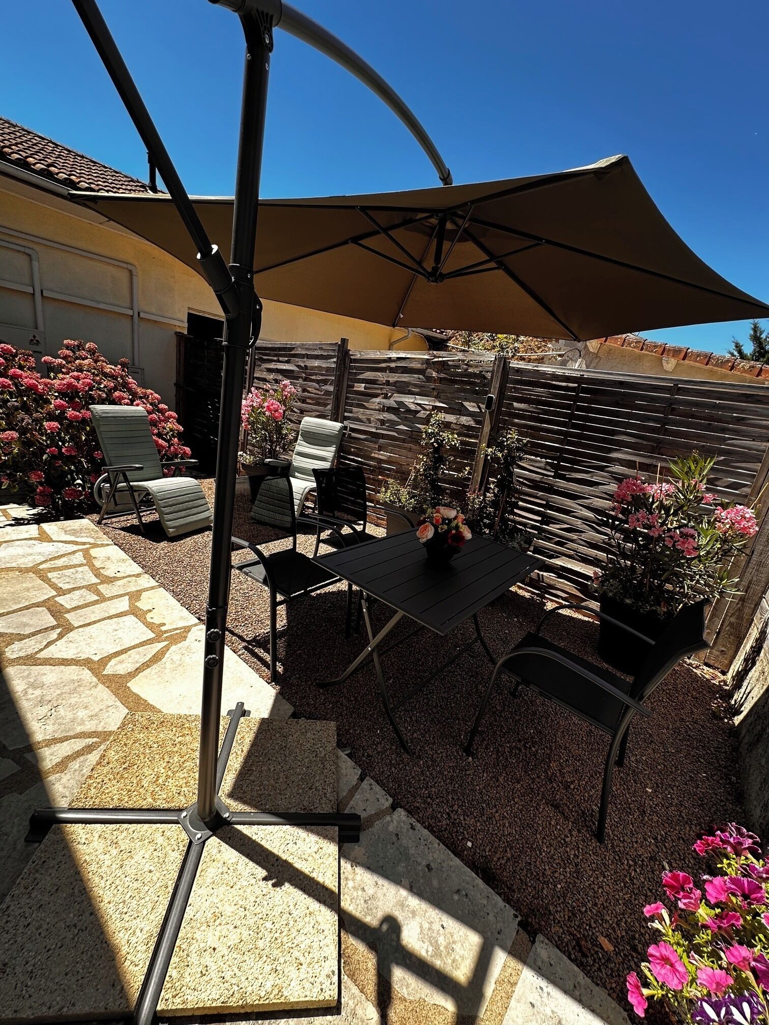 En udendørs terrasse med bord og stole, en pergola og et træhegn.