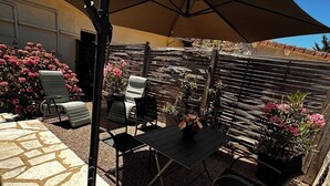 An outdoor patio with a table and chairs, a pergola, and a wooden fence.