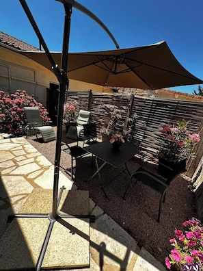 Une terrasse extérieure avec une table et des chaises, une pergola et une clôture en bois.
