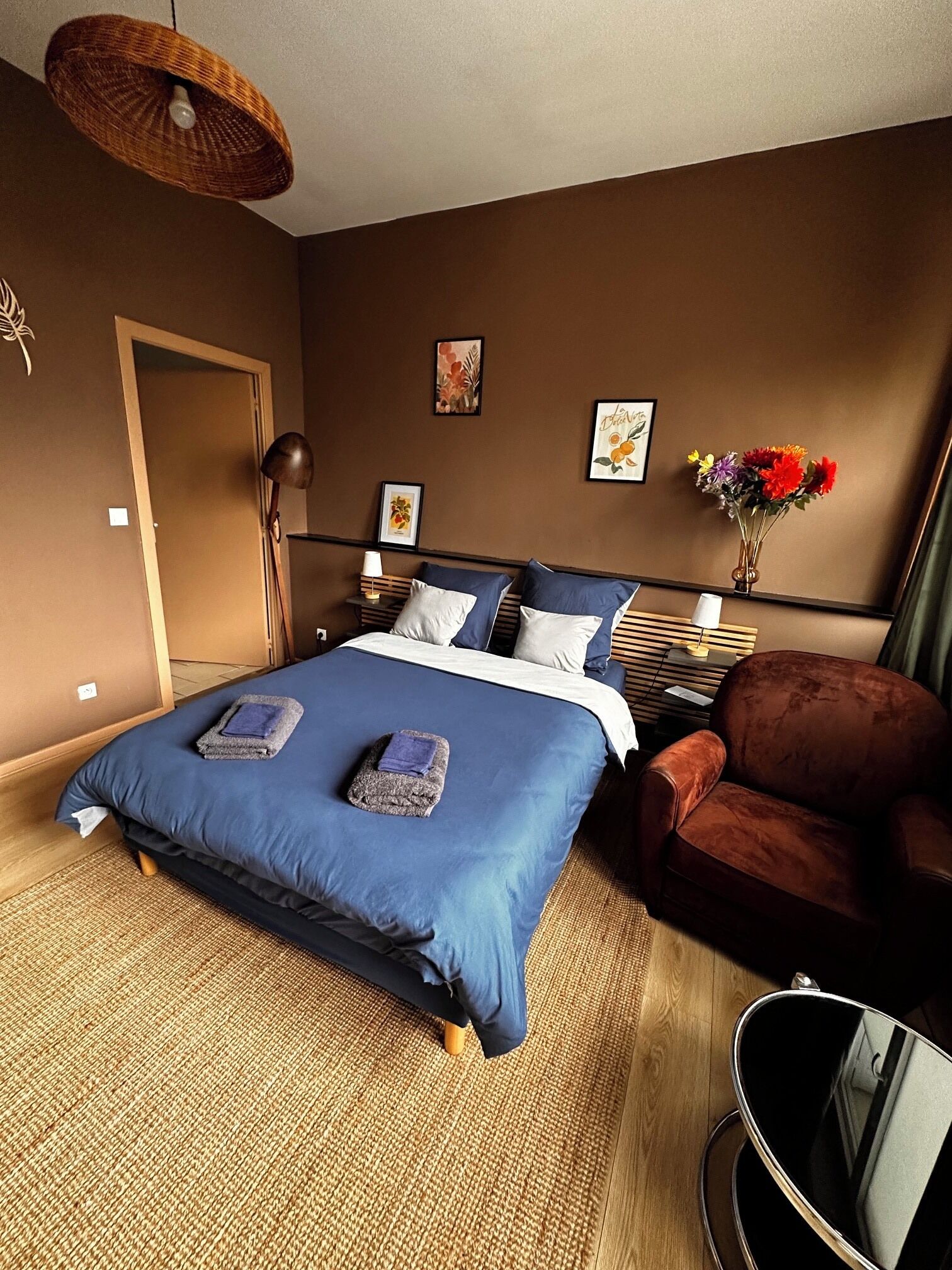 Une chambre d’hôtel avec un lit, une chaise, une table de chevet et une lampe fixée au mur.