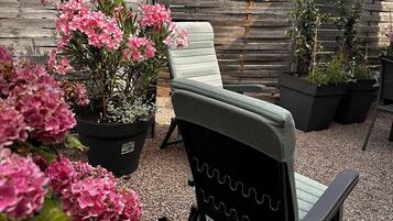 Un espace patio aménagé avec un fauteuil de relaxation, des plantes en pot et une clôture en bois.