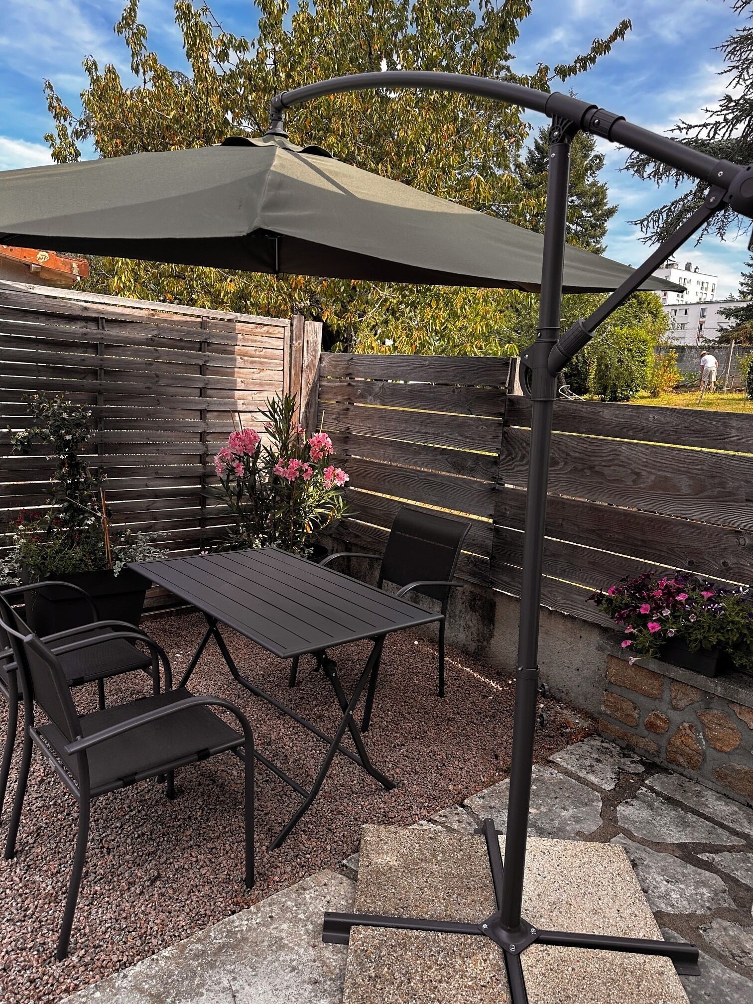 An outdoor patio with a table and chairs, a wooden fence, and a pergola with a canopy.