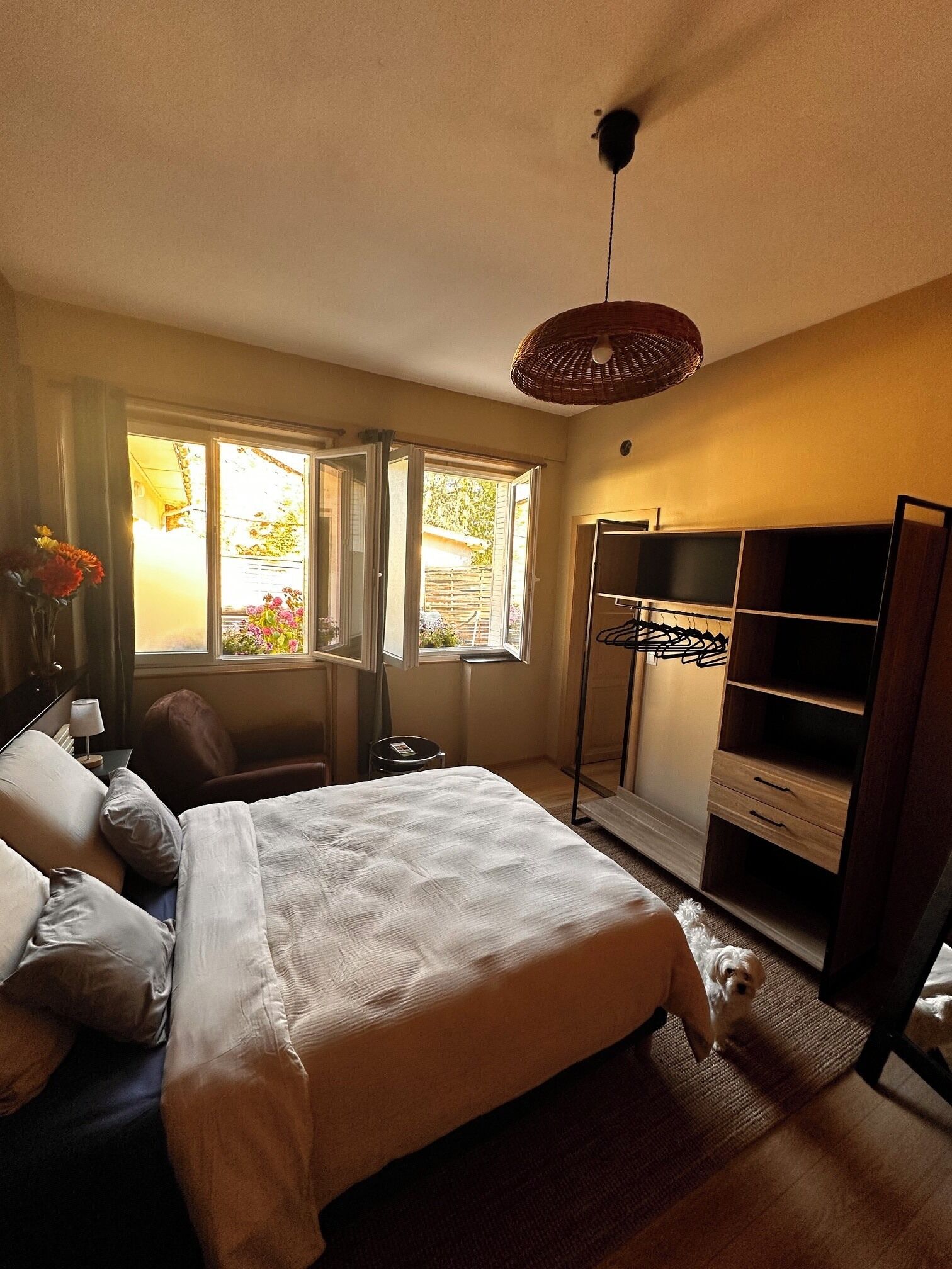 Een slaapkamer met een bed, een kast, een stoel en een raam met uitzicht op groen.