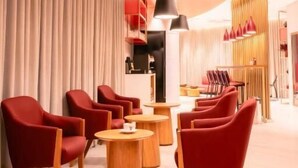Ein modernes Interieur mit roten Stühlen und runden Tischen, Holzboden und Pendelleuchten.