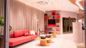 Ein modernes Wohnzimmer mit einem roten Sofa, Holztischen und einem Fernseher auf einem roten Regal.