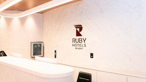 Ein moderner Hotel-Empfangsbereich mit Marmorwand, dem Logo der Ruby Hotels und einem Empfangsschalter.