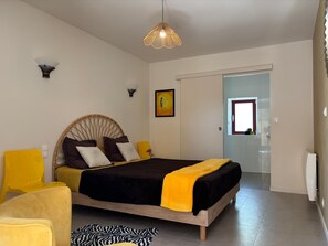A bedroom with a bed, a chair, a rug, and a door leading to another room.