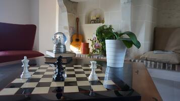 A chessboard with pieces, a guitar, and a potted plant in a living room.