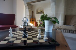 Un tablero de ajedrez con piezas, una guitarra y una planta en maceta en una sala de estar.