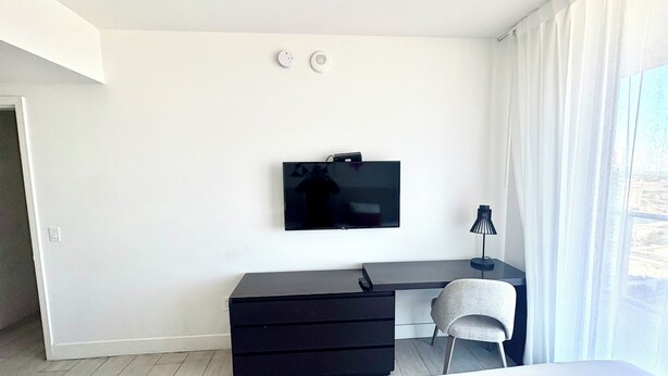 A modern hotel room with a flat-screen TV mounted on the wall, a desk with a chair, and a bed. - 3-bedroom At Hyde Beach House Hollywood With Gym, Beach & Pool Service (Hollywood)