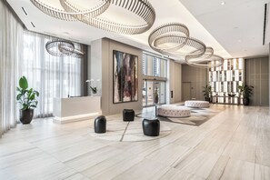 Eine geräumige Lobby mit einer Rezeption, modernen Leuchten und einem großen Fenster.