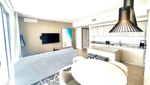 A modern hotel room with a flat-screen TV, a dining area with a round table, and a kitchen with a built-in stove. - 3-bedroom At Hyde Beach House Hollywood With Gym, Beach & Pool Service (Hollywood)