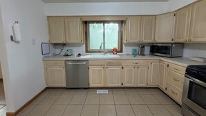A kitchen with light-colored cabinets, a dishwasher, a microwave, and a stove. - The Woodlands Charity  -Large Private Room & bath in Tallmadge (Tallmadge)