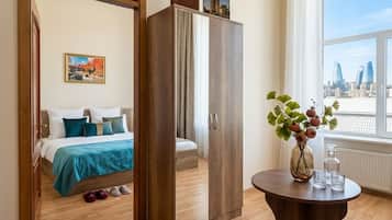 Een hotelkamer met een bed, kledingkast, rond tafel en uitzicht op de stad.