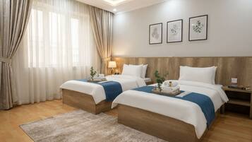 A hotel room with two beds, a wooden headboard, a nightstand, a lamp, and a large window with curtains.