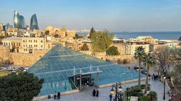 A large glass structure with a geometric design, surrounded by a plaza with benches and potted plants.