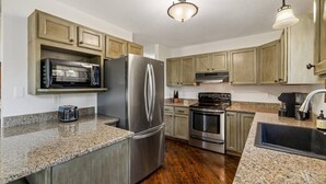 A kitchen with wooden cabinets, stainless steel appliances, granite countertops, and a built-in microwave. - Forest Road Haven: 3 King BR-GameRoom-HotTub-Sauna (Rapid City)