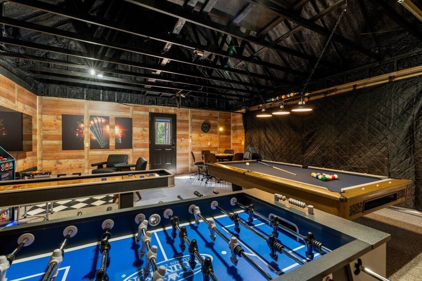 A room with a foosball table, pool table, and a billiards table.
