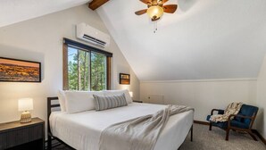 A bedroom with a bed, a nightstand, a chair, a ceiling fan, and a window. - Forest Road Haven: 3 King BR-GameRoom-HotTub-Sauna (Rapid City)
