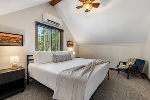 Ein Schlafzimmer mit Bett, Nachttisch, Stuhl, Deckenventilator und Fenster.