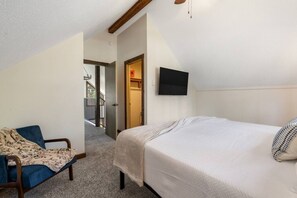 A bedroom with a bed, a chair, a television, and a door leading to a balcony. - Forest Road Haven: 3 King BR-GameRoom-HotTub-Sauna (Rapid City)