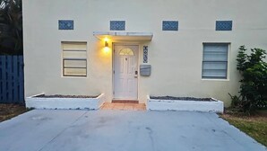 Ett hus med en vit dörr, en liten veranda och en brevlåda.