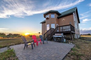 A two-story building with a balcony, outdoor seating, and a barbecue grill. - Teton Homestead: Bear Creek Cabin Retreat (Driggs)