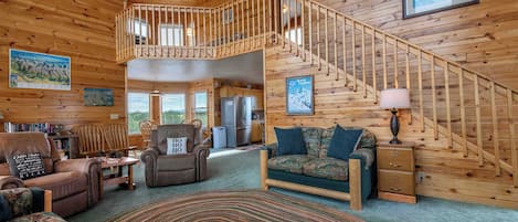Un intérieur de cabine spacieux, avec un escalier en bois, un coin salon confortable et un espace repas.
