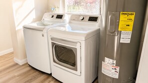 A laundry room with two front-loading washing machines and a stainless steel dryer.