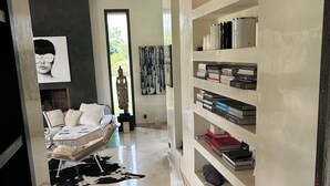 Ein modernes Wohnzimmer mit einem weißen Sofa, einem schwarz-weißen Teppich und einem Bücherregal voller Bücher und Dekoration.