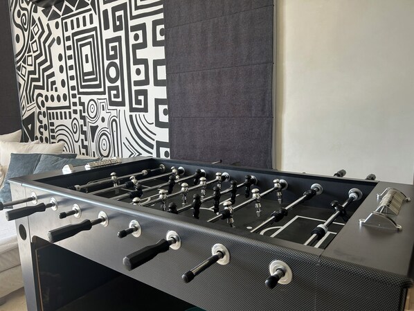 A foosball table in a room with a patterned wall and a bed with pillows. - "Le Chameau Bleu" Villa: Wellness & Luxury on a 1.5-hectare private estate (Marrakech)