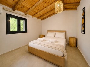 A bedroom with a wooden ceiling, a bed with white linens, a window with black frames, and a wall-mounted artwork. - Villa Elea - Two Bedroom Villa, Sleeps 4 (Kato Garouna)
