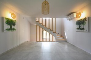 A modern interior with a staircase, wall-mounted artwork, and pendant lighting. - Villa Natalia - Four Bedroom Villa, Sleeps 8 (Kato Garouna)