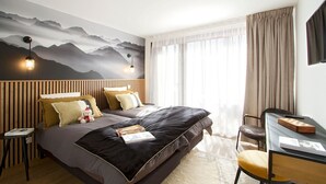 Ein modernes Schlafzimmer mit Bett, Nachttischen, einem Schreibtisch und einem großen Fenster mit Vorhängen.