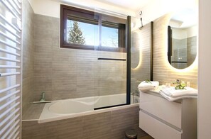 Une salle de bain moderne avec une douche à parois de verre, une baignoire et un meuble-lavabo avec un miroir.