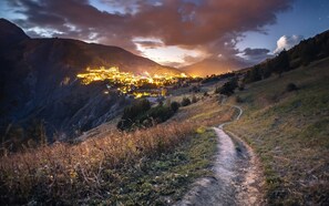 A valley with a path leading to a lit-up town nestled in the mountains. - Super Venosc | T3 à 100m des pistes, 50m télésiège (MONT-DE-LANS)