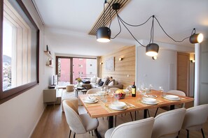 Un espace repas avec une table en bois dressée pour six personnes, entourée de chaises blanches.