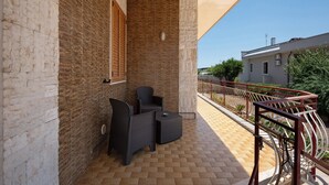 A balcony with a wicker sofa and chairs, a tiled floor, and a metal railing. - Apartment 'Alle Colonne Bianche Rooms' with Balcony, Wi-Fi and Air Conditioning (Conversano)