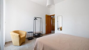 A bedroom with a bed, a chair, a floor lamp, a mirror, and a wardrobe. - Apartment 'Alle Colonne Bianche Rooms' with Balcony, Wi-Fi and Air Conditioning (Conversano)
