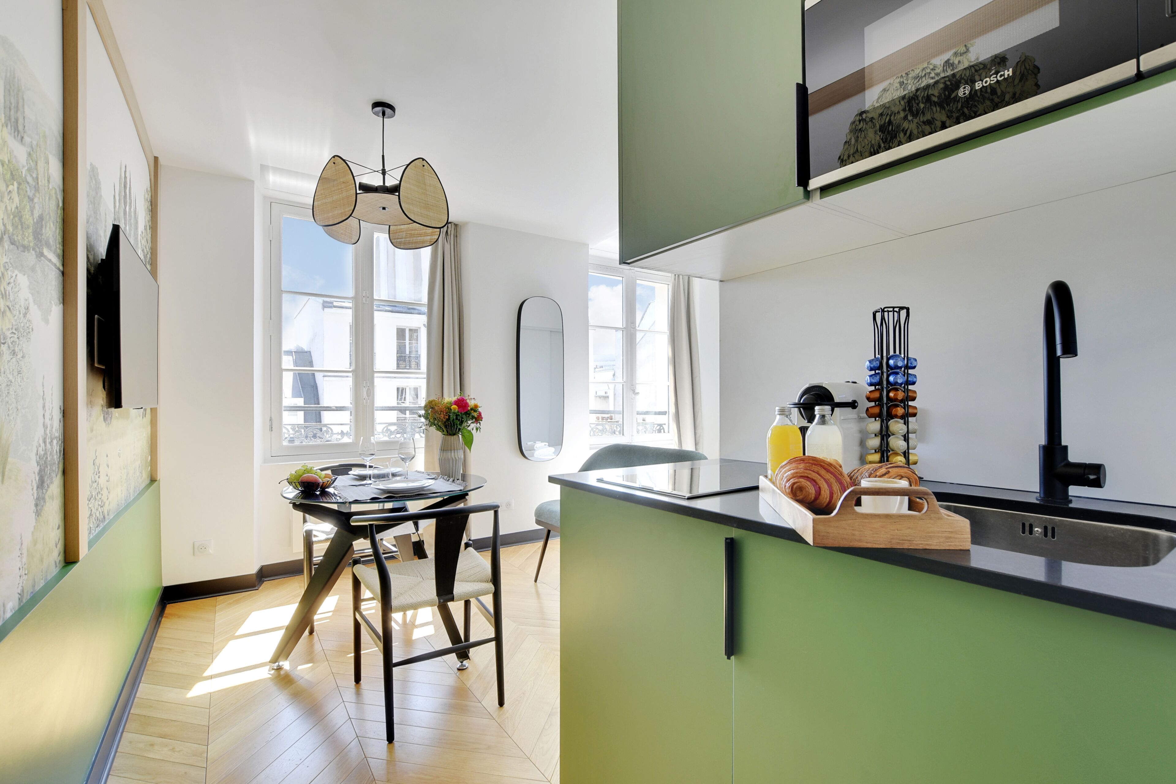 Une cuisine moderne avec un coin repas, comprenant une table ronde, des chaises et une vue sur la ville grâce à de grandes fenêtres.