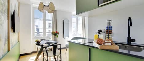 Une cuisine moderne avec un coin repas, comprenant une table ronde, des chaises et une vue sur la ville grâce à de grandes fenêtres.