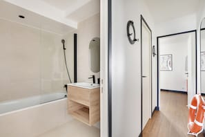 Ein modernes Badezimmer mit einer Badewanne, einem Holzkosmetikschrank und einem Spiegel.