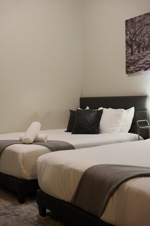 Ein Hotelzimmer mit zwei Betten, einem Kopfteil und einem Bild an der Wand.