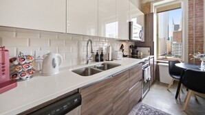 A modern kitchen with white cabinets, stainless steel appliances, and a view of the city through a large window. - Stylish Downtown Stay | Pool, Gym, Valet Parking (Dallas)